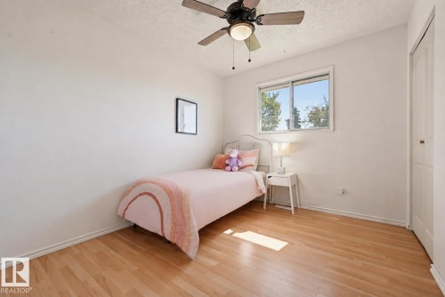 Wood-finish flooring, ceiling fan with integrated lighting, a sliding window, and a built-in closet with bi-fold doors - 6768 39 Avenue Nw, Edmonton, AB - Indoor Photo Showing Bedroom