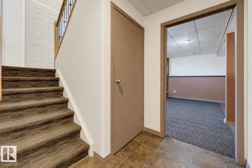 Carpeted staircase with dark metal and wood railing - 6768 39 Avenue Nw, Edmonton, AB - Indoor Photo Showing Other Room