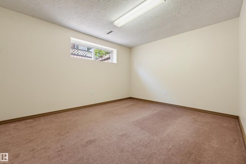 Recessed window opening, neutral wall paint, textured ceiling, flush-mount fluorescent lighting, and wall-to-wall carpeting - 6768 39 Avenue Nw, Edmonton, AB - Indoor Photo Showing Other Room