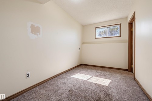 Carpeted room featuring a window with wood-frame trim and a wood-paneled door frame - 6768 39 Avenue Nw, Edmonton, AB - Indoor Photo Showing Other Room