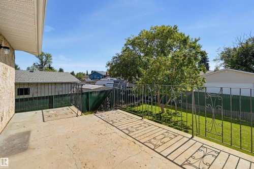 Expansive concrete patio with decorative metal railing overlooking a fenced yard and mature trees - 6768 39 Avenue Nw, Edmonton, AB - Outdoor
