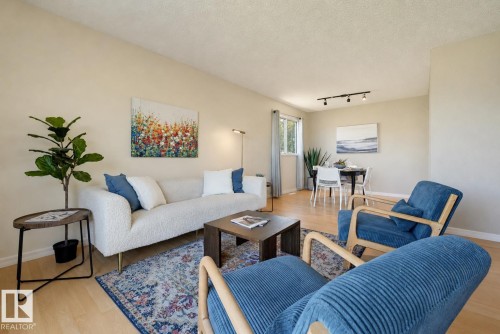 Open-concept living area with wood-finish flooring, neutral wall tones, and track lighting - 6768 39 Avenue Nw, Edmonton, AB - Indoor Photo Showing Living Room