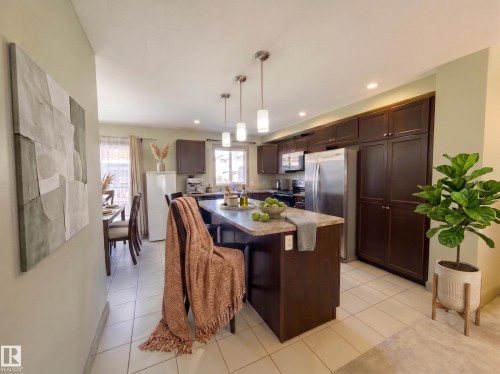 Kitchen featuring dark wood-finish cabinetry, stainless steel appliances, recessed lighting, and a center island with pendant lighting - #29 1150 Windermere Wy Sw, Edmonton, AB 