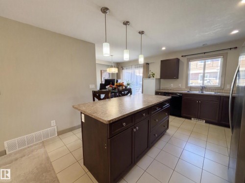 Kitchen featuring a center island, dark wood-finish cabinetry, tile flooring, and pendant lighting - #29 1150 Windermere Wy Sw, Edmonton, AB 