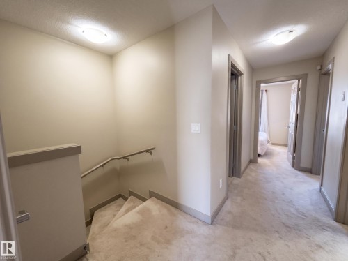 Hallway with neutral wall paint, overhead flush mount lighting, and gray trim - #29 1150 Windermere Wy Sw, Edmonton, AB 