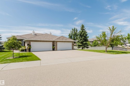 Brick exterior residence featuring a multi-car garage, mature landscaping, and an expansive driveway - 6604 Sandin Cove Nw, Edmonton, AB - Outdoor