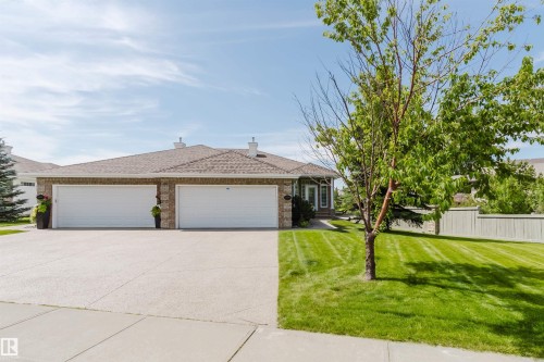 Brick facade property featuring two white garage doors, a concrete driveway, and a shingle roof - 6604 Sandin Cove Nw, Edmonton, AB - Outdoor