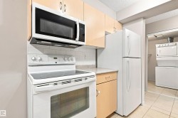 Kitchen featuring light wood-finish cabinetry, white appliances, and a tiled backsplash - 