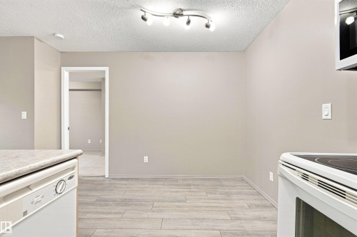Neutral-toned walls complement wood-finish flooring - #117 17011 67 Av Nw, Edmonton, AB - Indoor Photo Showing Kitchen