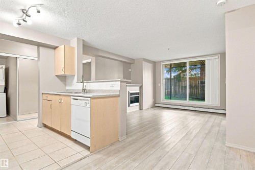 Functional kitchen with light wood-finish cabinetry, granite-style countertops, and a full-size dishwasher - #117 17011 67 Av Nw, Edmonton, AB - Indoor Photo Showing Kitchen