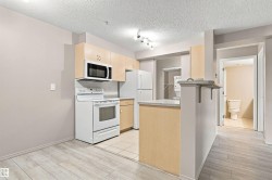 Kitchen featuring light wood-finish cabinetry, white appliances, and a tiled backsplash - 