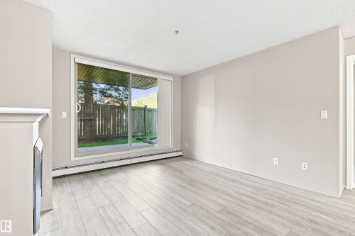 Light wood-finish flooring with a neutral wall color - #117 17011 67 Av Nw, Edmonton, AB - Indoor Photo Showing Other Room