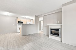 Modern fireplace with a white mantel, light wood-finish flooring, light-toned cabinetry, and white appliances - 