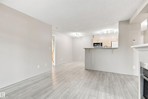 Light wood-finish flooring, recessed lighting, track lighting, light gray walls, built-in microwave - #117 17011 67 Av Nw, Edmonton, AB - Indoor Photo Showing Other Room