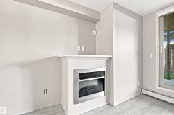 Electric fireplace with white mantel, light gray wall paint, light-toned wood-finish flooring, and sliding glass patio door - 