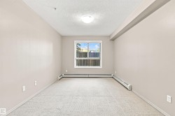 Neutral-toned wall paint, textured ceiling, window with vertical blinds, baseboard heating units, and light-toned carpet flooring - 