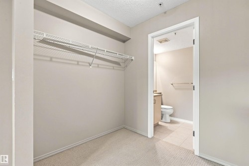 Carpeted room featuring a wire shelving system and an entryway to a tiled bathroom - #117 17011 67 Av Nw, Edmonton, AB - Indoor With Storage