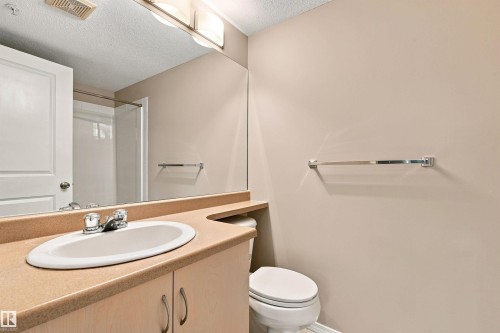 Built-in vanity with an integrated sink, dual-handle faucet, and light wood-finish cabinetry - #117 17011 67 Av Nw, Edmonton, AB - Indoor Photo Showing Bathroom