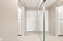 White paneled doors, mirrored sliding closet doors, tiled flooring, and light neutral wall tones - #117 17011 67 Av Nw, Edmonton, AB  - Indoor Photo Showing Other Room 