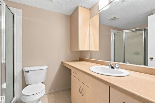 Spacious vanity with an integrated sink and chrome faucet, ample under-counter storage, full-width mirror, and a glass-enclosed shower - #117 17011 67 Av Nw, Edmonton, AB - Indoor Photo Showing Bathroom