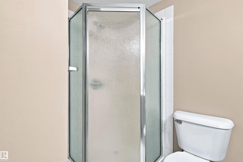 Corner shower with textured glass enclosure and chrome framing - #117 17011 67 Av Nw, Edmonton, AB - Indoor Photo Showing Bathroom