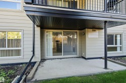 Ground-level patio with concrete surface, direct exterior access via sliding glass door, and overhead balcony for shelter - 
