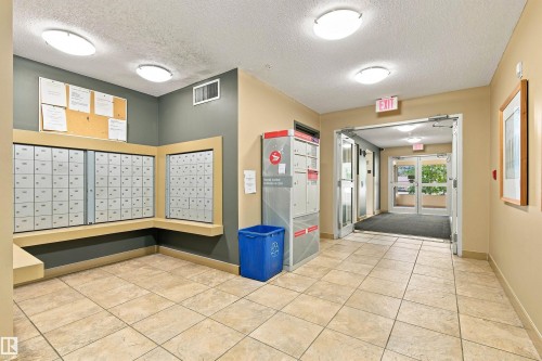 Tiled floor entry with recessed lighting, wall-mounted mailboxes, and double glass doors - #117 17011 67 Av Nw, Edmonton, AB - Indoor Photo Showing Other Room