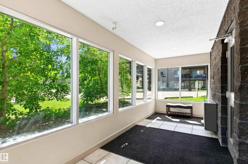 Hallway featuring large windows, white ceiling, recessed lighting, and tile flooring - #117 17011 67 Av Nw, Edmonton, AB -  With Exterior