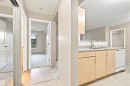 Kitchen featuring light wood-finish cabinetry, a stainless steel sink with a gooseneck faucet, light countertop, and a white dishwasher - #117 17011 67 Av Nw, Edmonton, AB  - Indoor Photo Showing Kitchen 