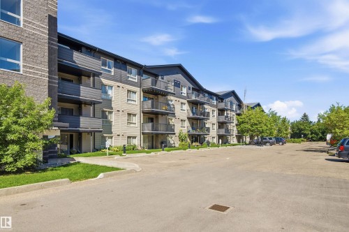 Multi-story residential building with private balconies and a paved parking area - #117 17011 67 Av Nw, Edmonton, AB - Outdoor With Facade