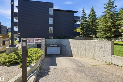 Underground parking access with concrete retaining walls and a garage door - #117 17011 67 Av Nw, Edmonton, AB - Outdoor
