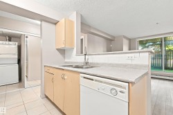 Kitchen with light wood-finish cabinetry, light-colored countertops, and a white tile backsplash - 