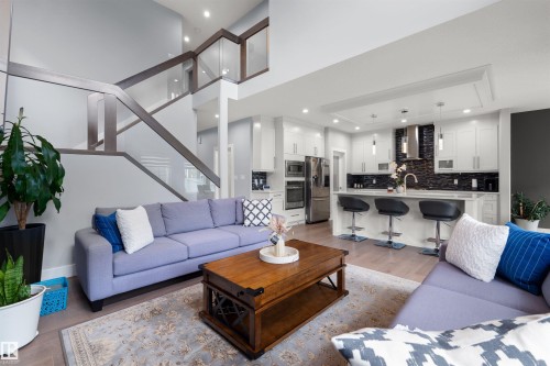 Open-concept living space featuring a modern kitchen with a large island and built-in stainless steel appliances - 16327 17 Avenue Sw, Edmonton, AB 