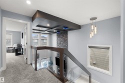 Modern glass and wood railing, recessed lighting, coffered ceiling detail, stacked stone accent wall, and contemporary pendant light fixture - 