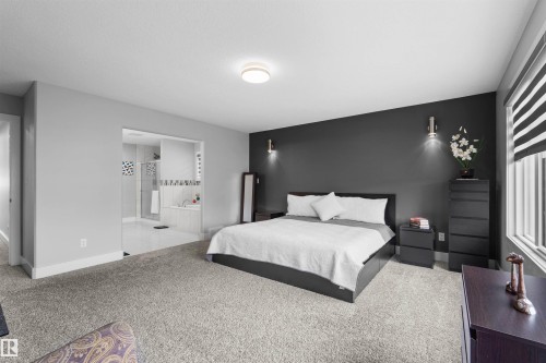 Spacious room with plush carpet flooring, a dark accent wall, and a large window with privacy blinds - 16327 17 Avenue Sw, Edmonton, AB 