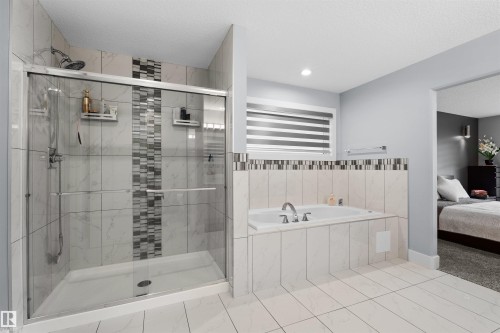 Glass-enclosed shower with a rainfall showerhead, and a built-in tub with chrome fixtures - 16327 17 Avenue Sw, Edmonton, AB 