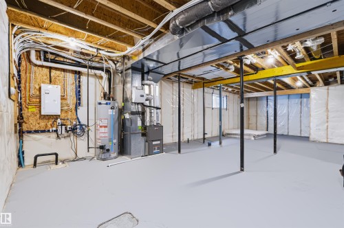 Unfinished basement with exposed ceiling joists, painted concrete flooring, a water heater, and a furnace unit - 16327 17 Avenue Sw, Edmonton, AB 