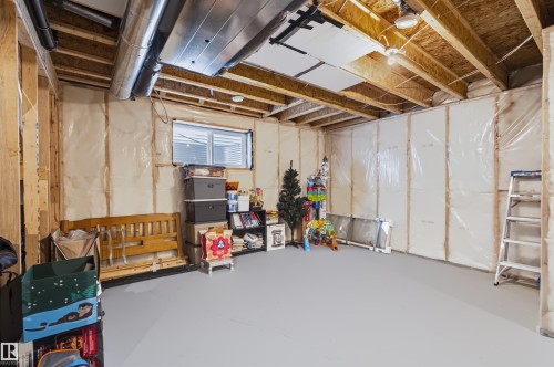 Unfinished basement with exposed wood framing, insulated walls, and a window with blinds - 16327 17 Avenue Sw, Edmonton, AB 