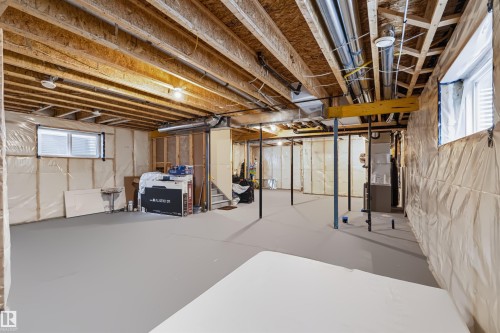 Unfinished lower level featuring exposed wood joists, structural support beams, concrete flooring, and multiple windows - 16327 17 Avenue Sw, Edmonton, AB 