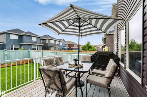 Raised wood-finish deck with white railings and an expansive green space - 16327 17 Avenue Sw, Edmonton, AB 