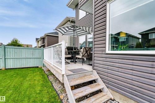 Rear deck with white railing, wood steps, and a large picture window - 16327 17 Avenue Sw, Edmonton, AB 