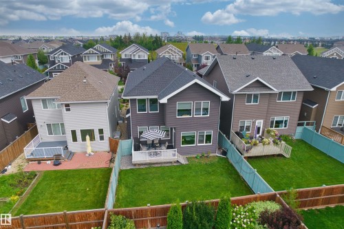 Rear exterior featuring a wood deck, a light blue fence, and a manicured lawn - 16327 17 Avenue Sw, Edmonton, AB 