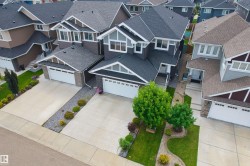 Contemporary two-story exterior with an attached two-car garage, concrete driveway, and front lawn landscaping - 