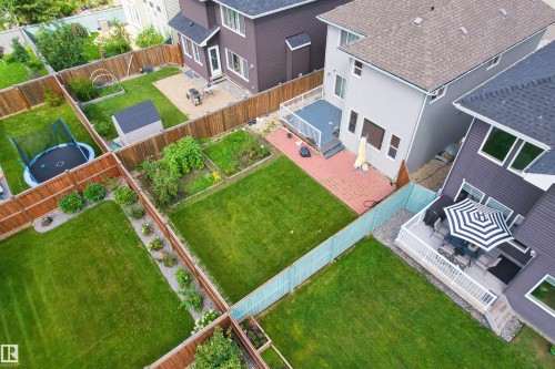 Expansive backyard featuring a manicured lawn, a garden bed, and a privacy fence - 16327 17 Avenue Sw, Edmonton, AB 