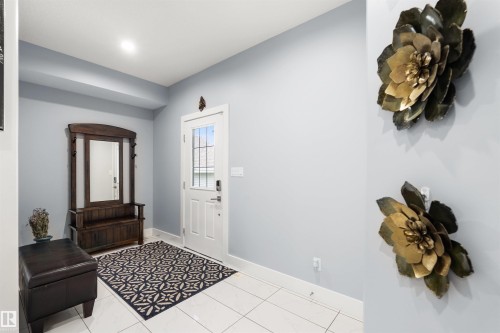 Entryway with white rectangular floor tiles, a white paneled door with integrated glass, and light-colored walls - 16327 17 Avenue Sw, Edmonton, AB 