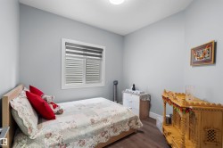 Wood-finish flooring, light gray wall paint, and a window with horizontal blinds - 
