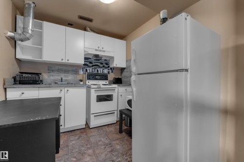Kitchen featuring white cabinetry, gray countertops, a mosaic tile backsplash, and tile flooring - 3425 48 Street Nw, Edmonton, AB - Indoor Photo Showing Kitchen