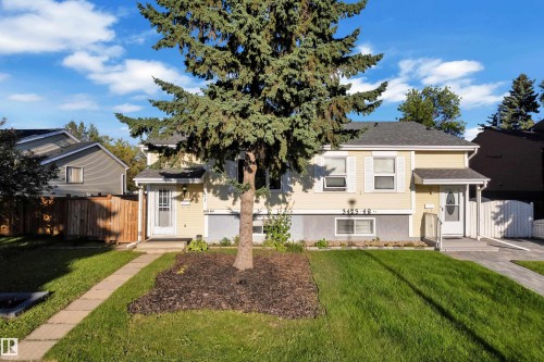 Two-story residence featuring light yellow siding, white window shutters, a front entry with a small porch, and a paved driveway - 3425 48 Street Nw, Edmonton, AB - Outdoor