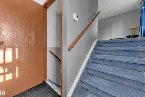 Staircase with blue carpeting and a wood handrail - 3425 48 Street Nw, Edmonton, AB - Indoor Photo Showing Other Room