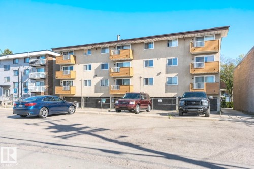 Four-story building with multiple balconies, textured stucco exterior, and a paved parking area - #106 10620 104 St Nw, Edmonton, AB - Outdoor With Balcony